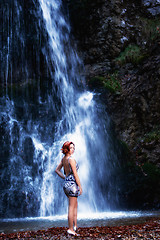 Image showing Red-haired woman in front of a waterfall