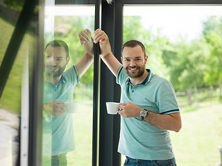 Image showing young man drinking morning coffee by the window