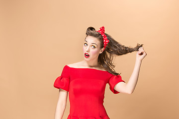 Image showing Beautiful young woman with pinup make-up and hairstyle. Studio shot on pastel background