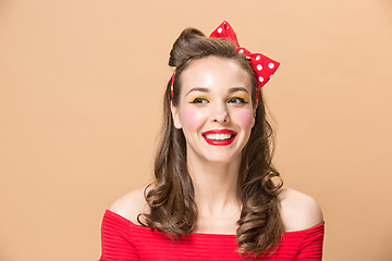 Image showing Beautiful young woman with pinup make-up and hairstyle. Studio shot on pastel background