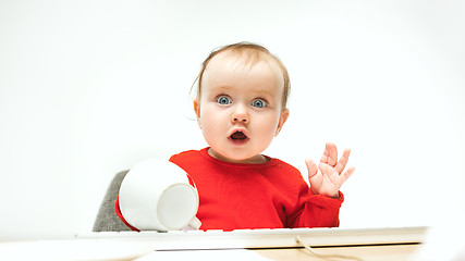 Image showing Happy child baby girl toddler sitting with keyboard of computer isolated on a white background