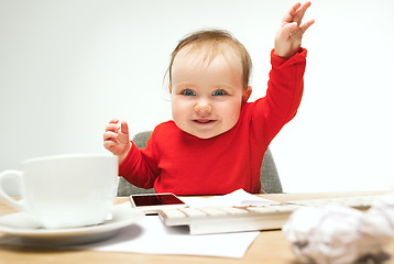 Image showing Happy child baby girl toddler sitting with keyboard of computer isolated on a white background