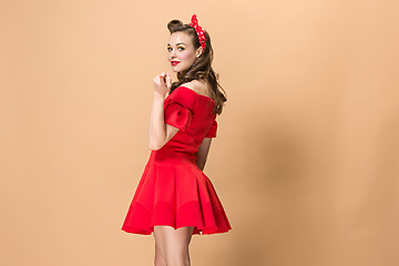 Image showing Beautiful young woman with pinup make-up and hairstyle. Studio shot on pastel background