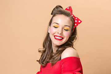 Image showing Beautiful young woman with pinup make-up and hairstyle. Studio shot on pastel background