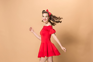 Image showing Beautiful young woman with pinup make-up and hairstyle. Studio shot on pastel background