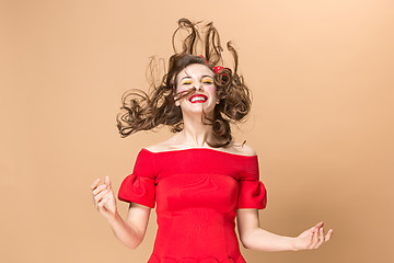 Image showing Beautiful young woman with pinup make-up and hairstyle. Studio shot on pastel background