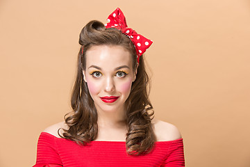 Image showing Beautiful young woman with pinup make-up and hairstyle. Studio shot on pastel background