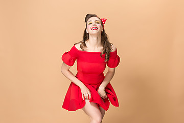 Image showing Beautiful young woman with pinup make-up and hairstyle. Studio shot on pastel background