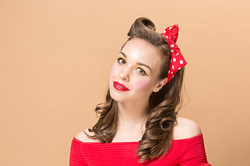 Image showing Beautiful young woman with pinup make-up and hairstyle. Studio shot on pastel background