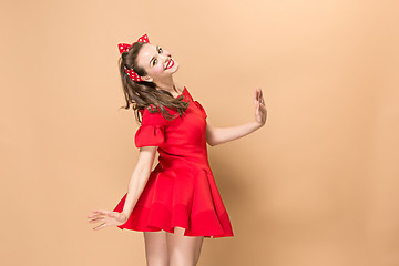 Image showing Beautiful young woman with pinup make-up and hairstyle. Studio shot on pastel background