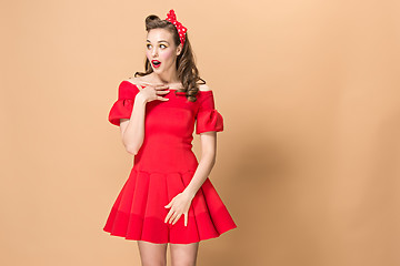 Image showing Beautiful young woman with pinup make-up and hairstyle. Studio shot on pastel background