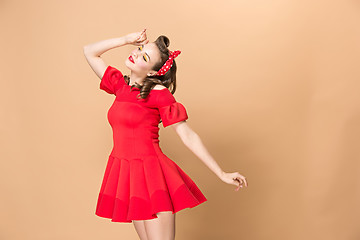 Image showing Beautiful young woman with pinup make-up and hairstyle. Studio shot on pastel background