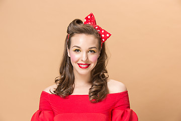 Image showing Beautiful young woman with pinup make-up and hairstyle. Studio shot on pastel background