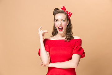 Image showing Beautiful young woman with pinup make-up and hairstyle. Studio shot on pastel background