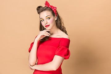 Image showing Beautiful young woman with pinup make-up and hairstyle. Studio shot on pastel background