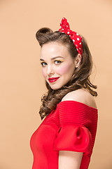 Image showing Beautiful young woman with pinup make-up and hairstyle. Studio shot on pastel background