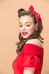 Image showing Beautiful young woman with pinup make-up and hairstyle. Studio shot on pastel background