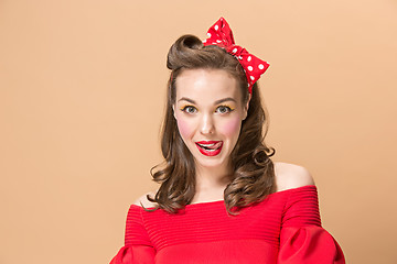 Image showing Beautiful young woman with pinup make-up and hairstyle. Studio shot on pastel background