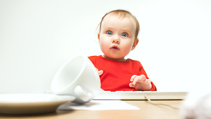 Image showing Happy child baby girl toddler sitting with keyboard of computer isolated on a white background