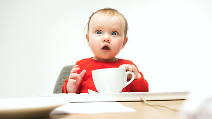 Image showing Happy child baby girl toddler sitting with keyboard of computer isolated on a white background