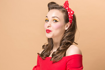 Image showing Beautiful young woman with pinup make-up and hairstyle. Studio shot on pastel background