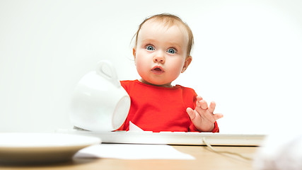 Image showing Happy child baby girl toddler sitting with keyboard of computer isolated on a white background