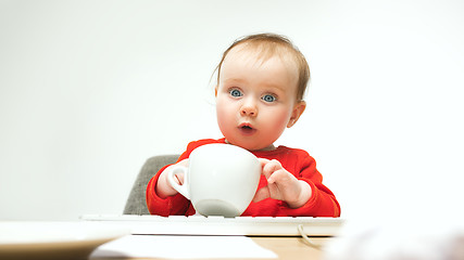 Image showing Happy child baby girl toddler sitting with keyboard of computer isolated on a white background