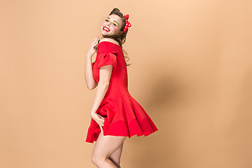 Image showing Beautiful young woman with pinup make-up and hairstyle. Studio shot on pastel background