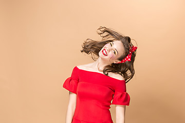 Image showing Beautiful young woman with pinup make-up and hairstyle. Studio shot on pastel background