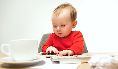 Image showing Happy child baby girl toddler sitting with keyboard of computer isolated on a white background