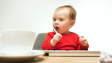 Image showing Happy child baby girl toddler sitting with keyboard of computer isolated on a white background