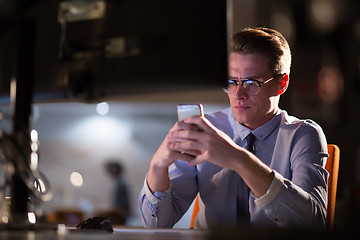 Image showing man using mobile phone in dark office