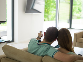 Image showing Young couple on the sofa watching television