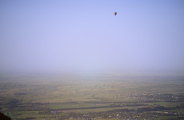 Image showing Hot air balloon above the green field and villages