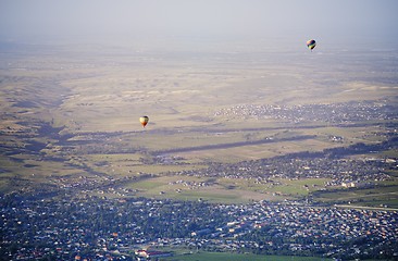 Image showing Hot air balloons above the green field and villages