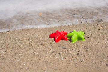 Image showing Red and green starfish-shaped molds on the sand