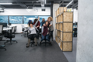 Image showing multiethnics business team racing on office chairs