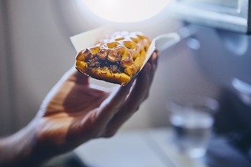 Image showing Passenger enjoying snack in airplane