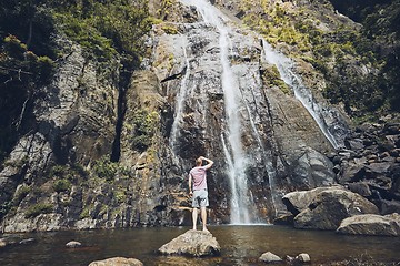 Image showing Man standing against waterfall