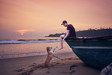 Image showing Young man with dog on the beach