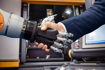 Image showing Hand of a businessman shaking hands with a Android robot.