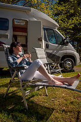 Image showing Woman is standing with a mug of coffee near the camper RV.