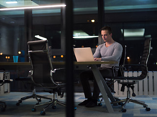 Image showing man working on laptop in dark office