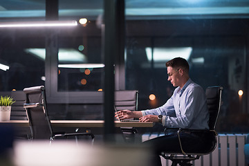 Image showing man working on laptop in dark office