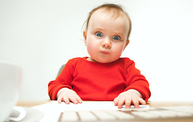 Image showing Happy child baby girl toddler sitting with keyboard of computer isolated on a white background