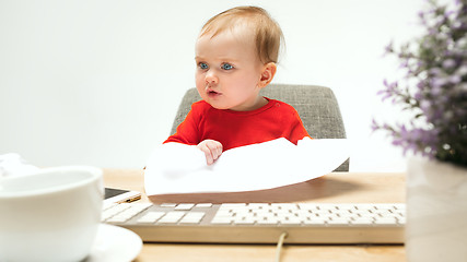 Image showing Happy child baby girl toddler sitting with keyboard of computer isolated on a white background