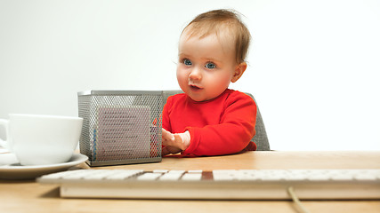 Image showing Happy child baby girl toddler sitting with keyboard of computer isolated on a white background