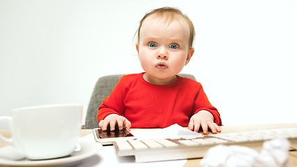 Image showing Happy child baby girl toddler sitting with keyboard of computer isolated on a white background