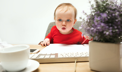 Image showing Happy child baby girl toddler sitting with keyboard of computer isolated on a white background