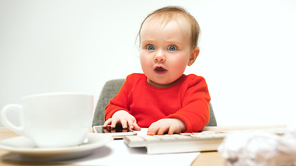 Image showing Happy child baby girl toddler sitting with keyboard of computer isolated on a white background